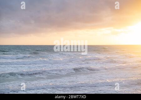 Tempesta Mare Jonio, Sud Italia, schiuma creata dal movimento delle onde nell'ora del tramonto in un giorno con cielo pieno di nuvole. Foto Stock