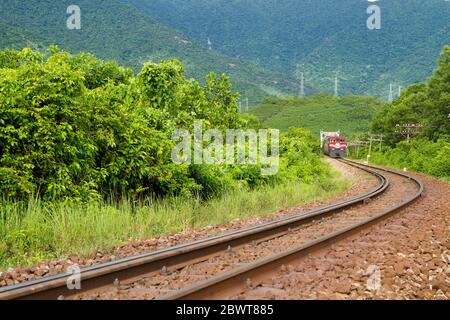 Treno è in esecuzione sulla ferrovia con vista montagna, alberi e ghiaia gialla in Hue - Vietnam Foto Stock