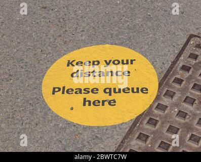 Social Distancing segno a ' mantenere la distanza, si prega di coda qui' a causa di Coronavirus (Covid-19) bloccato a terra in Devon Rurale, Inghilterra, UK Foto Stock