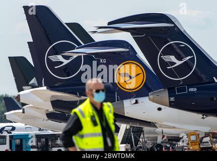 Monaco, Germania. 03 giugno 2020. Un uomo che indossa una maschera si trova di fronte a vari aerei Lufthansa che si trovano fianco a fianco al terminal. Lufthansa sta riprendendo il collegamento Monaco-Los Angeles dall'aeroporto di Monaco su 03.06.2020. Credit: Peter Kneffel/dpa/Alamy Live News Foto Stock