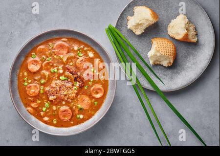 Zuppa di gumbo di pollo e salsiccia in ciotola grigia su fondo di cemento. Gumbo è la zuppa di cucina cajun della louisiana con roux. Cibo americano. Etn tradizionale Foto Stock