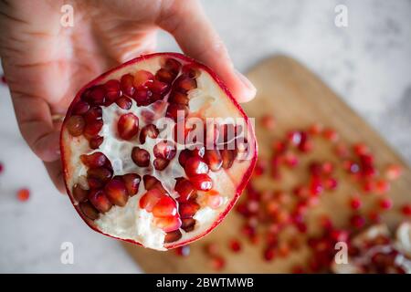 Mano di donna che tiene il melograno a metà Foto Stock