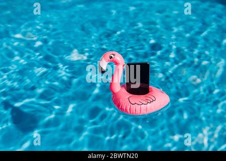 Smartphone su float rosa in piscina Foto Stock