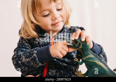 Sorridente bambina che gioca con dinosauro giocattolo Foto Stock