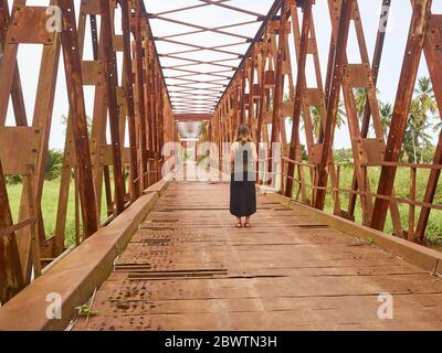 Benin, Dipartimento di Mono, Grand-Popo, Donna in piedi nel mezzo di vecchio ponte di ferro Foto Stock