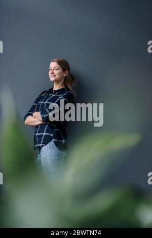 Ritratto di giovane donna grinning in piedi a un muro Foto Stock