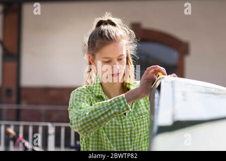 Giovane donna che getta rifiuti nel cestino di riciclaggio Foto Stock