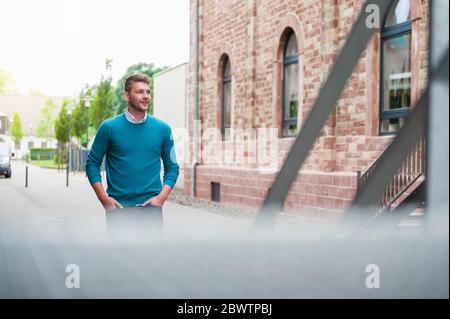 Giovane uomo d'affari che cammina lungo un edificio in mattoni Foto Stock