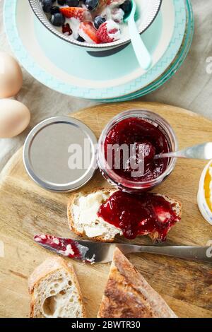 Pane con marmellata e ciotola di muesli di frutta sul tavolo della colazione Foto Stock