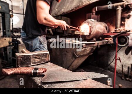 Coltello che lavora in forno di fusione, coltello finito su incudine in primo piano Foto Stock