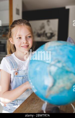 Ritratto di sorridente ragazza che guarda il globo Foto Stock