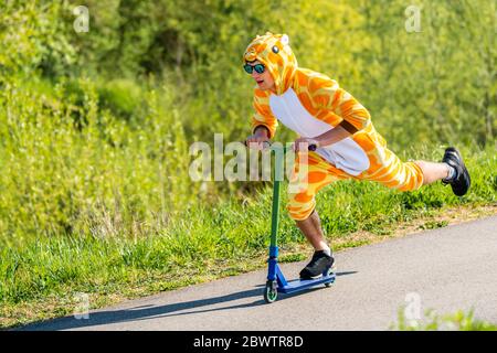 Giovane uomo che indossa costume da giraffa su scooter Foto Stock