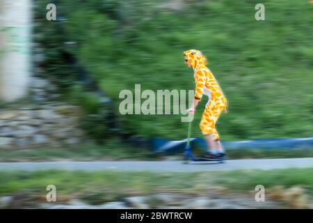 Giovane uomo che indossa costume da giraffa su scooter Foto Stock