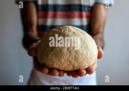 Mani dell'uomo che tengono la palla di impasto, primo piano Foto Stock