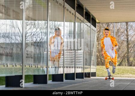 Giovane uomo che indossa giraffe costume longboard Foto Stock