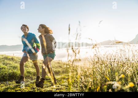 Due amici donne che camminano su un prato in montagna, Achenkirch, Austria Foto Stock