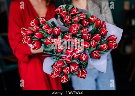 Primo piano di due donne che mostrano tulipani rossi Foto Stock