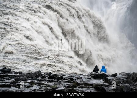 Primo piano di una infuriante cascata islandese con una costa rocciosa nera in primo piano Foto Stock