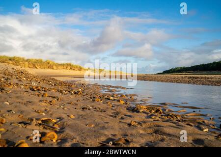 Una vista bassa di una spiaggia di sabbia e del ruscello a Holkham Beach, North Norfolk, Inghilterra, Regno Unito Foto Stock