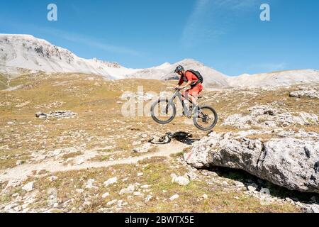 Uomo in mountain bike, Valle Munestertal, Grigioni, Svizzera Foto Stock