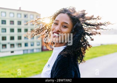 Ritratto di giovane donna con boccoli che colano i capelli in controluce Foto Stock