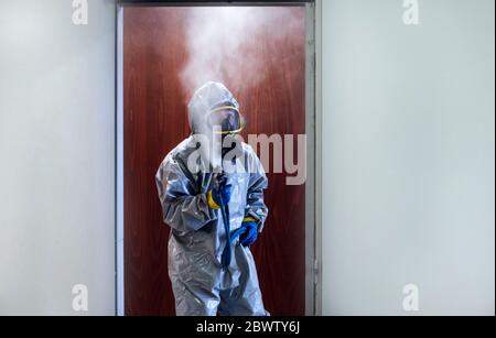 Personale addetto alla pulizia che desinfetta l'ospedale da virus scandalosi, indossando indumenti protettivi Foto Stock