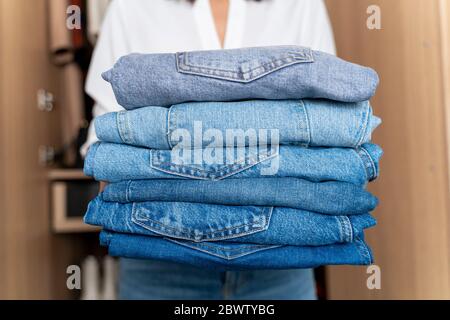 Donna che tiene una pila di jeans blu Foto Stock
