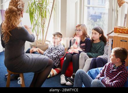 Bambini in classe durante il tempo della storia con l'insegnante Foto Stock