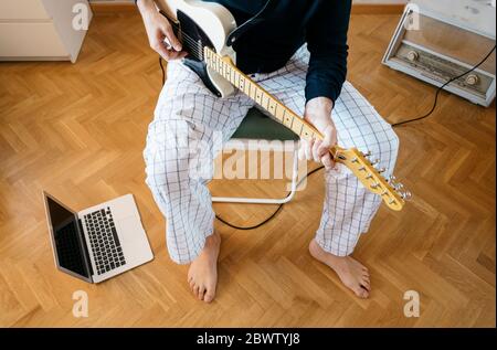 Vista di ritaglio di un uomo che suona la chitarra elettrica a casa Foto Stock