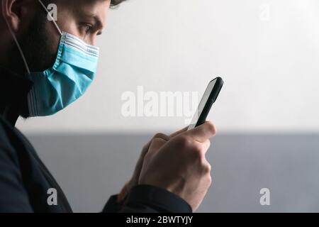 Uomo che indossa messaggi di testo mascherati sul telefono cellulare Foto Stock