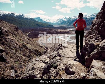 Vista posteriore di Woman su una roccia che ammira le viste sulle montagne, El Chalten, Argentina Foto Stock