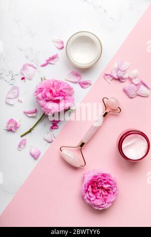 posare piatto di cosmetici rosa . Vista dall'alto composizione estetica.crema idratante per il viso, massaggiatore al quarzo Foto Stock