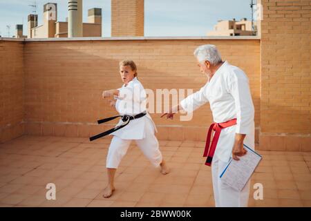 Donna con insegnante durante l'allenamento di karate sulla terrazza Foto Stock