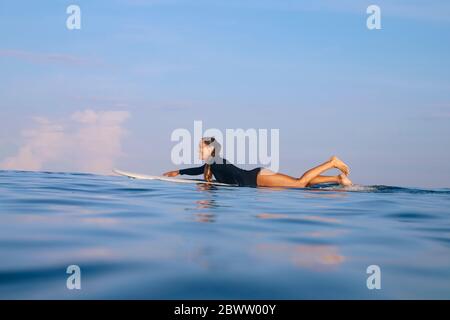 Donna felice che giace sul surf nel mare, Bali, Indonesia Foto Stock