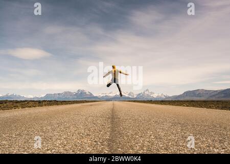 Uomo che salta su una strada in un paesaggio remoto a Patagonia, Argentina Foto Stock