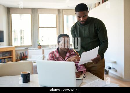 Giovane coppia afroamericana che va oltre le loro fatture insieme a casa Foto Stock