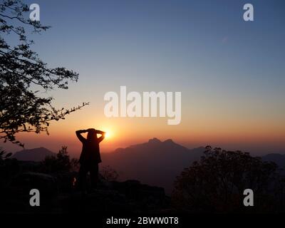 Silhouette di donna che guarda il tramonto, Serra da Leba, Angola Foto Stock