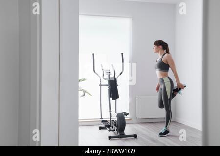 Donna che esegue esercizi di stretching prima di un allenamento a casa Foto Stock