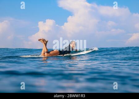 Donna felice che giace sul surf nel mare, Bali, Indonesia Foto Stock