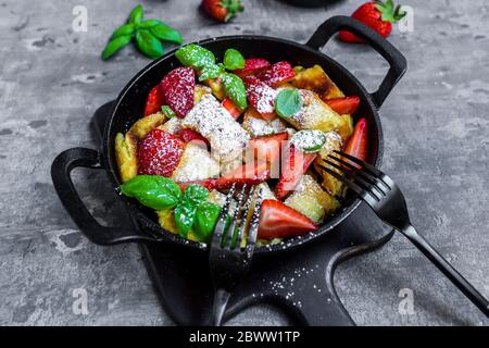 Padella di Kaiserschmarrn con fragole, zucchero in polvere e basilico Foto Stock