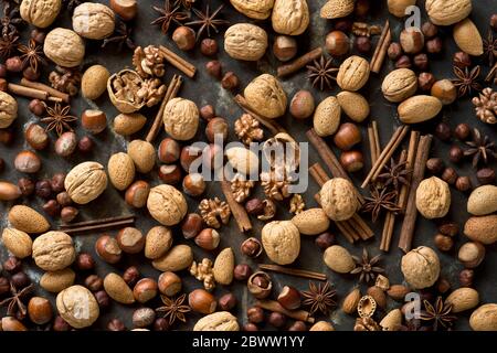 Anice stellato, bastoncini di cannella e varie noci che giacciono su una teglia rustica Foto Stock