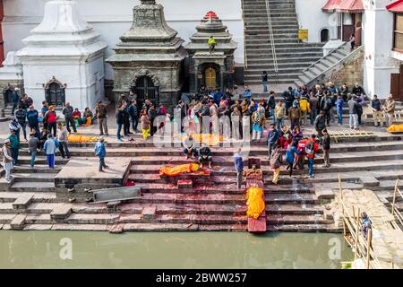 Kathmandu, Nepal - Febbraio 12,2018: Le persone indù che offrono preghiere religiose ai corpi morti prima di cremarsi al Tempio di Bagmati River Pashupatinath Foto Stock