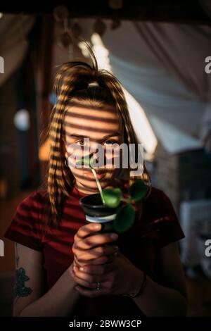 Giovane donna che tiene la pianta di zucchine a casa Foto Stock