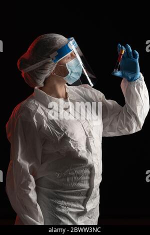 Donna in usura protettiva che tiene il campione di sangue Foto Stock