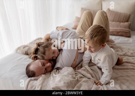 Padre che si stende a letto trascorrendo del tempo con i suoi due figli Foto Stock