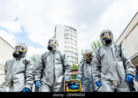 Vista ad angolo basso del lavoratore sanitario che cammina in tute protettive in città Foto Stock