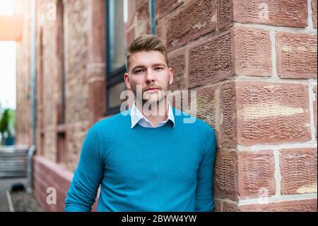 Ritratto di un giovane uomo d'affari appoggiato su un edificio in mattoni Foto Stock