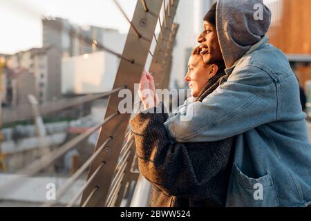 Affettuosa giovane coppia su un ponte al tramonto Foto Stock