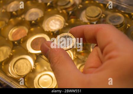 La mano dell'uomo contiene 1 moneta da un'accumulazione Foto Stock