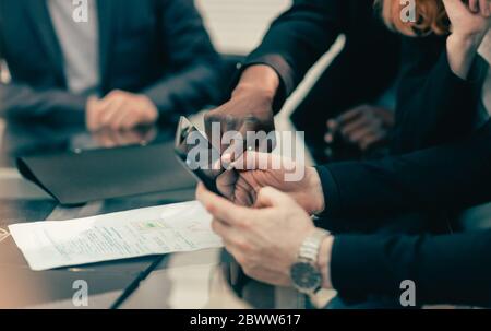primo piano. i colleghi di lavoro visualizzano i messaggi su uno smartphone Foto Stock